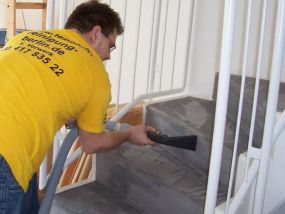 Mitarbeiter reinigt Treppenstufen mit Auslegware