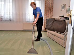 Mitarbeiterin reinigt Veours-Teppichboden mintgrün